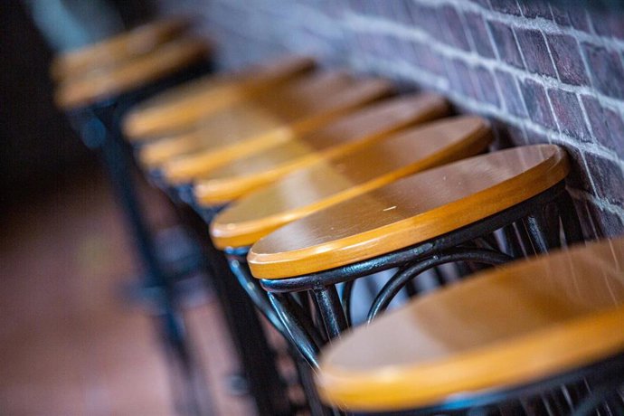 Taburetes vacíos en la barra de un bar.