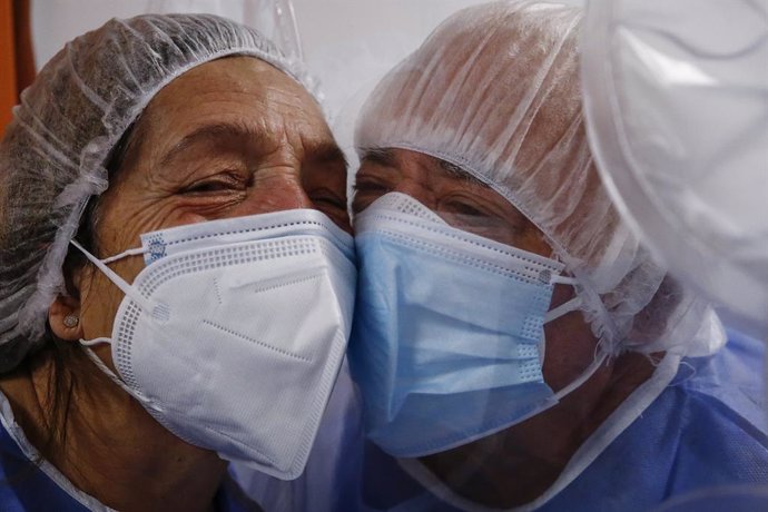 14 January 2021, Italy, Rome: A woman embraces her husband, who's infected with COVID-19, through the embrace tent at the New Castelli's Hospital which allows patients to have contact with family members during the COVID-19 hospitalization period. Photo