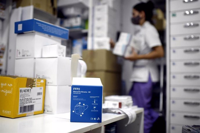 Vista de una de las cajas de test de antígenos para Covid-19 mientras una farmaceútica coloca varios productos en su farmacia, en Madrid (España). 