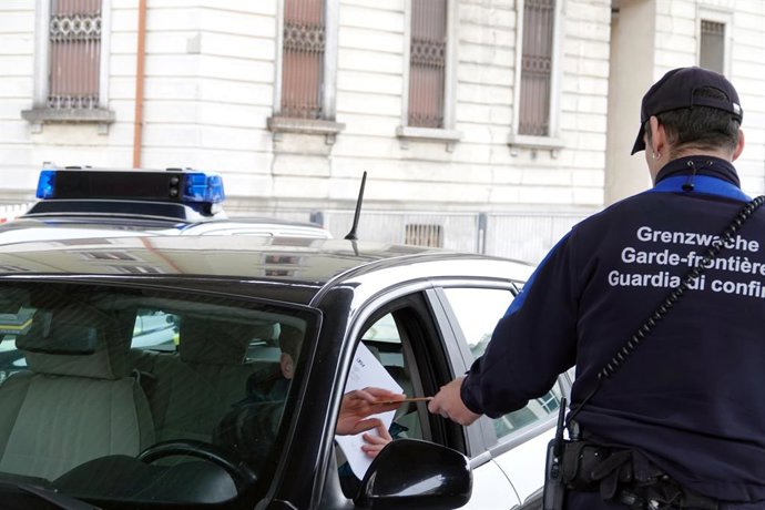 10 March 2020, Switzerland, Chiasso: A customs officer checks the papers of a man crossing the border at the Swiss-Italian border crossing. Cars have been queuing in front of the Swiss border guards who check papers since Italy has imposed an extensive 