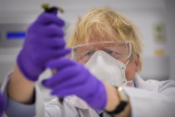 HANDOUT - 28 January 2021, United Kingdom, Edinburgh: UK Prime Minister Boris Johnson tries his hand at one of the tests as he visits the French biotechnology laboratory Valneva in Livingston where they will be producing a Covid-19 vaccine on a large sc