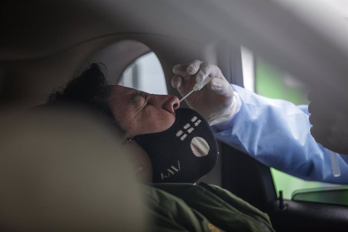 22 May 2020, Colombia, Bogota: A medical worker takes a sample of a driver at a drive-through COVID-19 testing centre which is launched by a private company in parking lots at the Colombian capital, where people could get tested without leaving their ca