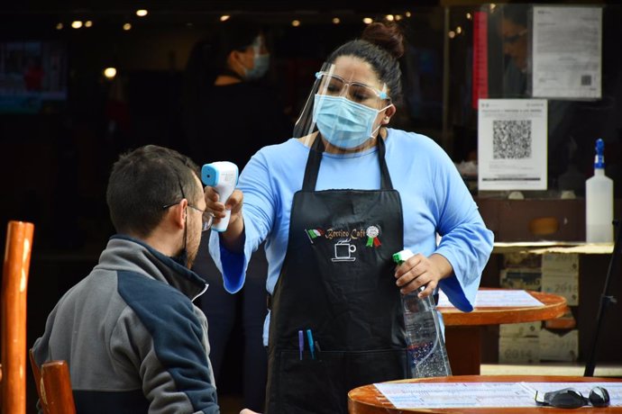 MEXICO CITY, MEXICO - JANUARY 20: A restaurant worker checks temperature to a customer after Mexico's Government allowed the restaurants reopen to operate only outdoors, after the restaurant industry protested against the confinement, although the pande