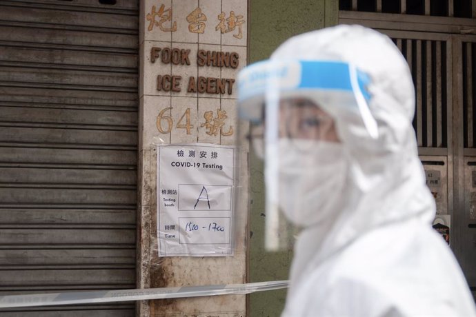 23 January 2021, China, Hong Kong: A health worker stands in front of a notice informing residents about time of compulsory coronavirus (COVID-19) test in a wall during lockdown imposed by the government to curb the spread of the pandemic. Photo: Ivan A