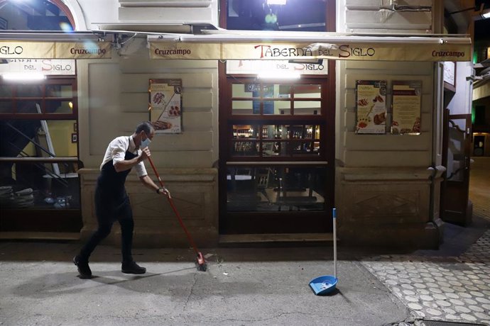 Dos camareros se afanan en recogen la terraza del bar ubicado en el centro de la capital, como  consecuencia del toque de queda impuesto por el Gobierno para poder frenar el contagio en Málaga a 27 de octubre 2020