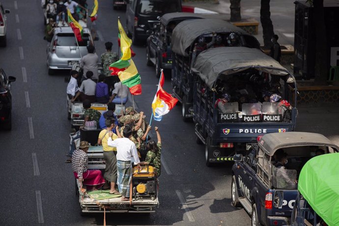 01 February 2021, Myanmar, Yangon: Trucks with the supporters of Myanmar military pass by police vehicles parked aside the streets of Yangon. Myanmar's military seized power on Monday and detained government officials including de facto leader Aung San 