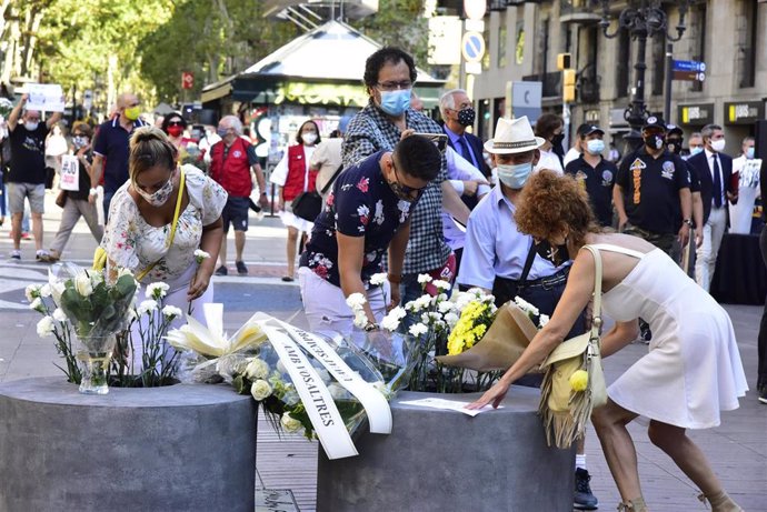 Asistentes dejan flores en recuerdo a las 16 personas fallecidas el 17 de agosto de 2017 y a los más de 150 heridos en los atentados de Barcelona y Cambrils durante el homenaje y minuto de silencio celebrado en Las Ramblas con motivo del tercer aniversa