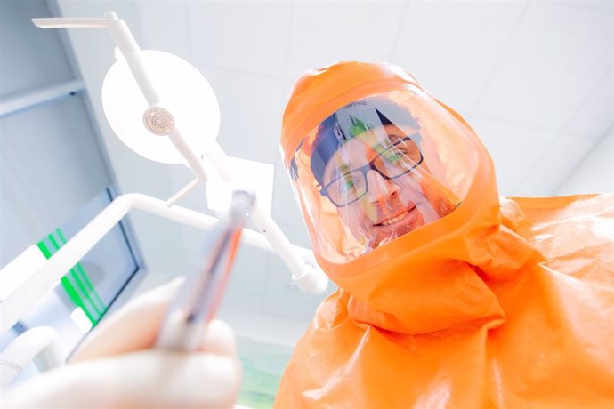 27 January 2021, North Rhine-Westphalia, Oberhausen: Ilker Sentuerk, dentist, holds a drill at a treatment room of his dental practice clinic while wearing a full FFp3 protective hood. Photo: Rolf Vennenbernd/dpa