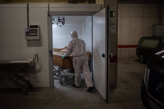 Un operario del Crematorio de Girona totalmente protegido traslada un ataúd de una víctima con COVID-19 para desinfectarlo antes de introducirlo en el horno crematorio. En Girona, Cataluña, (España), a 6 de mayo de 2020.