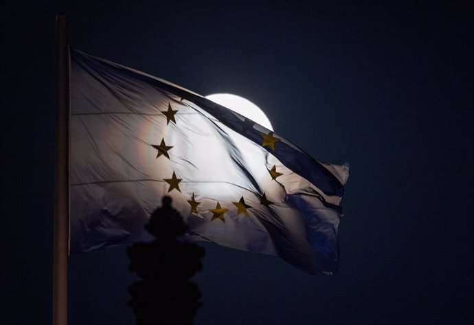 07 April 2020, Berlin: The so-called pink supermoon rises behind an EU flag on the Reichstag building. Photo: Christophe Gateau/dpa