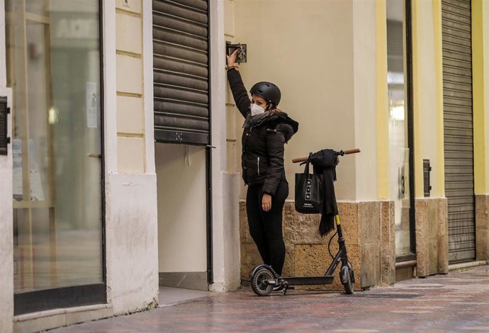 La trabajadora de un comercio cierra su establecimiento el primer día del cierre total de la hostelería y de tiendas a las 18.00h en Valencia, Comunidad Valenciana (España), a 21 de enero de 2021.
