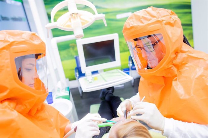 27 January 2021, North Rhine-Westphalia, Oberhausen: Ilker Sentuerk (R), dentist, and Sultan Ekmen, dental assistant in training, treat a patient while wearing FFP3 full protective hoods. Photo: Rolf Vennenbernd/dpa