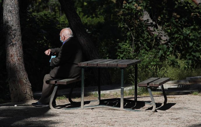 Un anciano con mascarilla descansa en el Parque Calero, en Madrid.