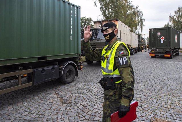 Soldado con mascarilla junto a un convoy militar para levantar un hospital de campaña en el recinto ferial de Praga, República Checa, para combatir el conronavirus
