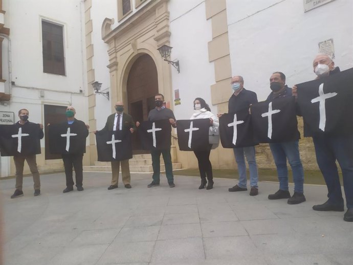 Alejandro Hernández con representantes de Vox sostienen las banderolas --con una cruz en blanco y un fondo negro-- para repartir entre los vecinos de Aguilar de la Frontera.