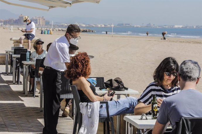 Varias personas disfrutan en la terraza de un bar junto a la playa después de que el Ministerio de Sanidad autorizara a que la totalidad de la Comunidad Valenciana pasase en su conjunto a la fase 1 de la desescalada. Las terrazas de los restaurantes y b