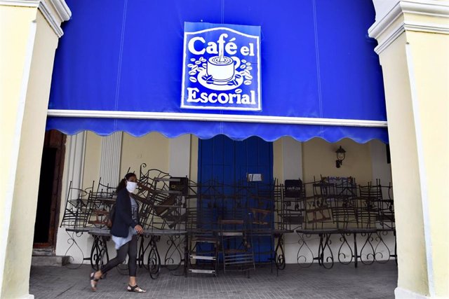 Una mujer pasea ante una cafetería en La Habana