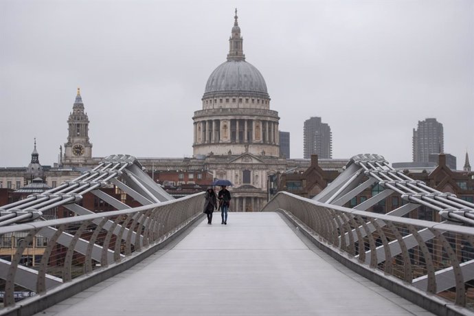 21 December 2020, England, London: Two people cross the quiet Millennium Bridge in London. UK Prime Minister Boris Johnson announced a strict lockdown and cancelled Christmas holiday gatherings across London and eastern and south-east England after scie