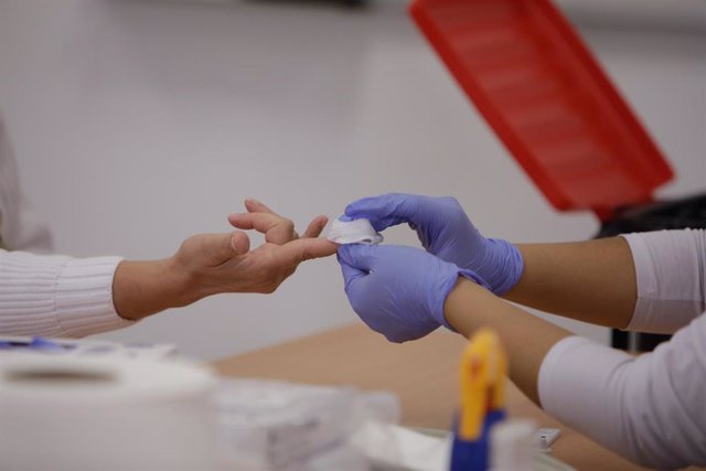 Personal sanitario de Cruz Roja saca sangre de un dedo a una persona para realizar el test rápido de detección de anticuerpos IgG e IgM en el Instituto de Formación Integral en Seguridad y Emergencias (IFISE).