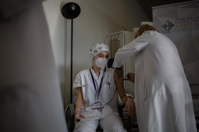Una infermera bovina a un professional sanitari amb la vacuna de Pfizer-BioNtech contra el COVID-19 a l'Hospital de la Santa Creu i Sant Pau de Barcelona, Catalunya (Espanya), a 14 de gener de 2021. 