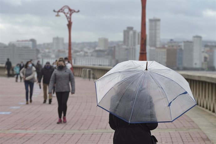 Una persona pasea con paraguas en el Paseo Marítimo en A Coruña, Galicia (España),