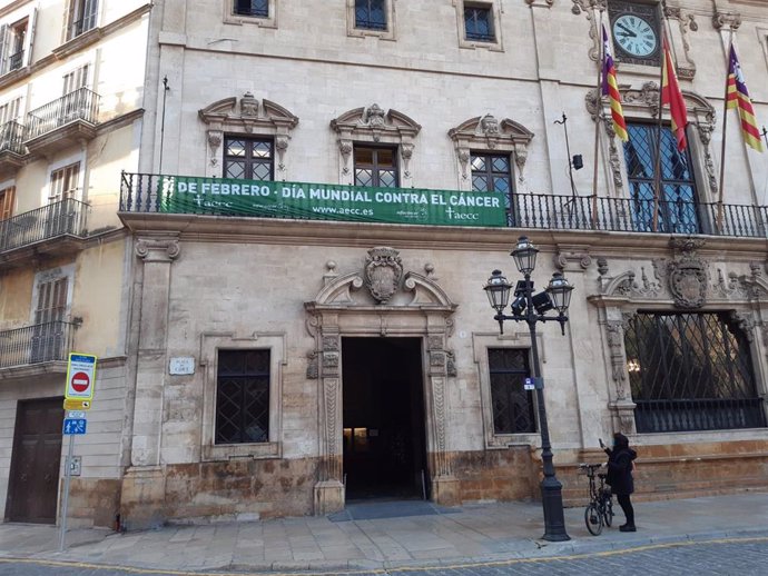 El Ayuntamiento de Palma cuelga una pancarta en su fachada con motivo del Día Mundial Contra el Cáncer.