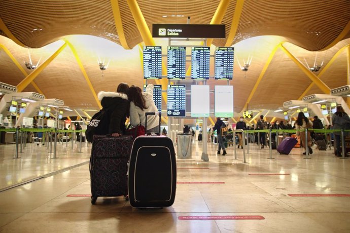 Dos viajeros señalando un panel de vuelo en la terminal T4 del Aeropuerto Adolfo Suárez Madrid-Barajas