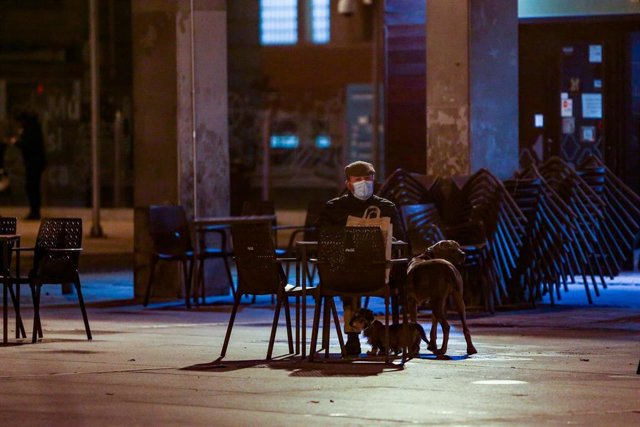 Un hombre con sus dos perros sentado en la terraza de un bar.
