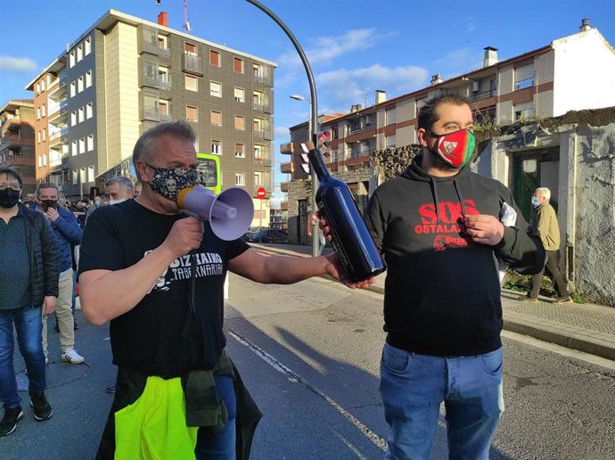Hosteleros participantes en la manifestación se pasan el testigo, una botella con un mensaje para el Gobierno Vasco.