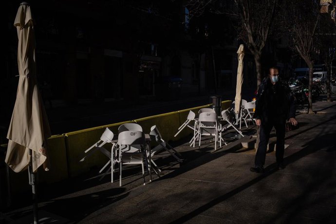 Un hombre pasa al lado de las sillas vacías de una terraza en Barcelona, en una imagen de archivo