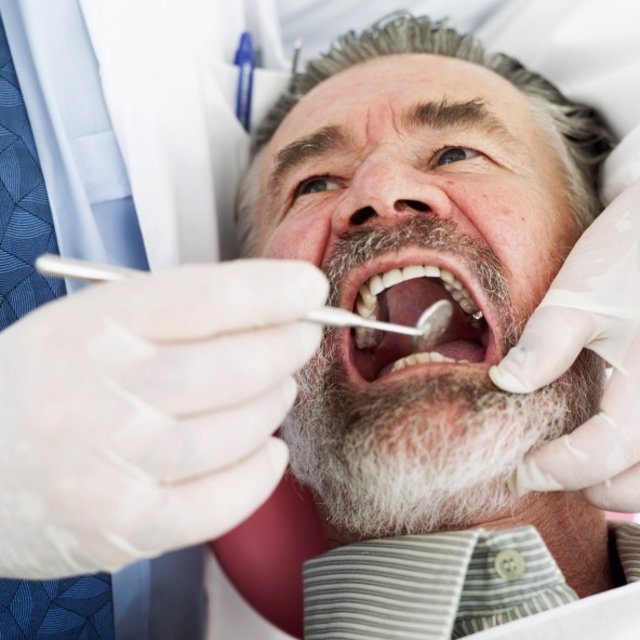 Close-up of a dentist examining a mature man