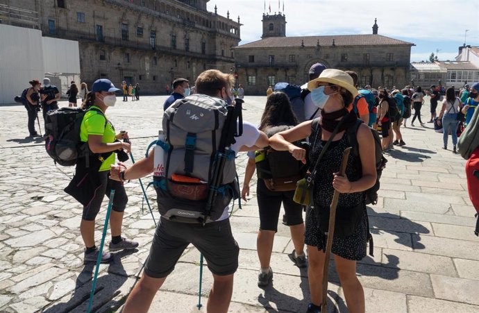 Peregrinos con mascarillas se saludan con el codo al llegar a la  Plaza del Obradoiro, en el primer verano de la pandamia Covid-19, Santiago de Compostela 26 de agosto del 2020