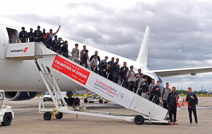 02 June 2019, England, Liverpool: Members of the Liverpool FC team pose for a picture with the trophy as they descend from their plane upon arrival at the John Lennon Airport a day after they won the UEFA Champions League final soccer match against Tott