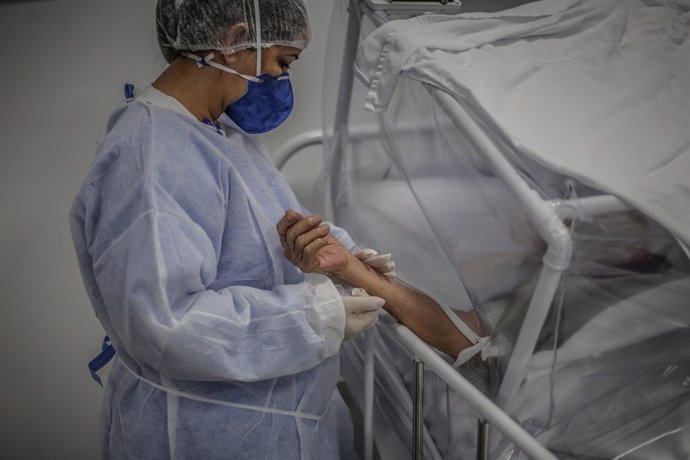 Una enfermera sujeta la mano de un paciente afectado por COVID-19 en Manaos.