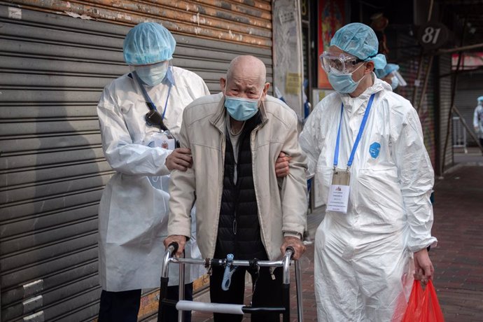 23 January 2021, China, Hong Kong: Health workers help an elderly resident returning home in an area where unprecedented lockdown has been declared by Hong Kong government in order to carry out compulsory coronavirus (COVID-19) testing in a designated z