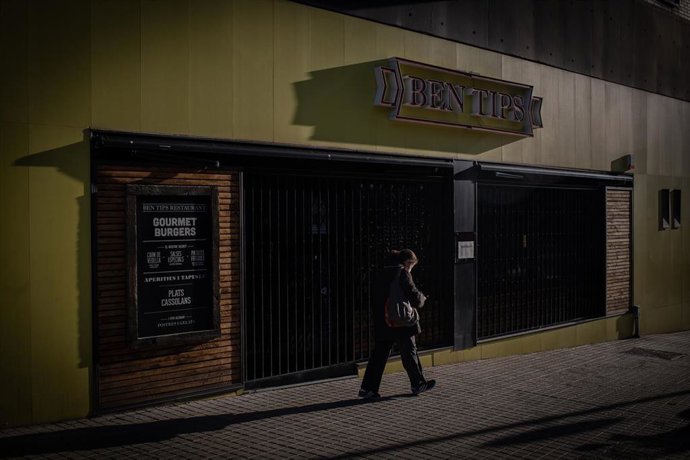 Un hombre pasa por un bar cerrado en Barcelona. Foto de archivo. 