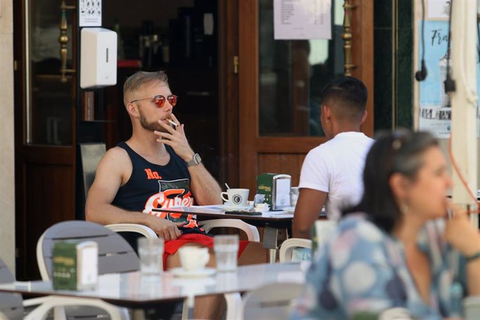 Una persona fuma en una terraza durante el primer día de la prohibición de realizarlo en la vía pública en Málaga, (Andalucía, España), a 17 de agosto de 2020.