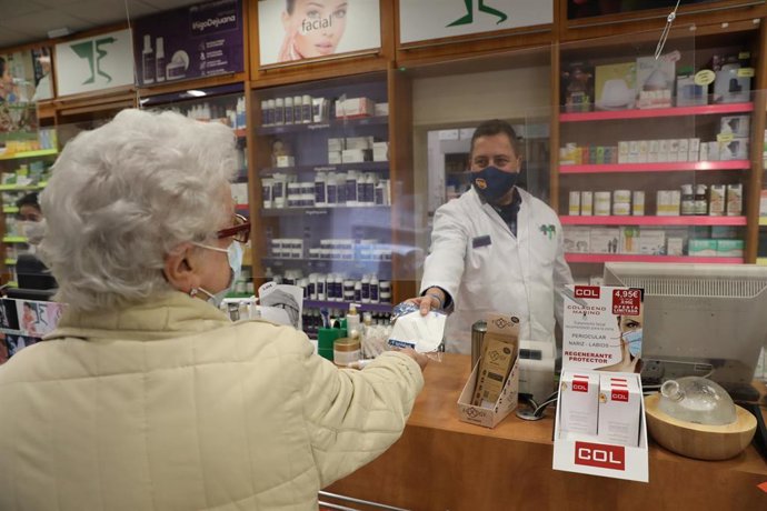 Una anciana recoge una mascarilla FFP2 en la farmacia situada en la C/Tucán (Carabanchel), en Madrid (España), a 4 de febrero de 2021. 