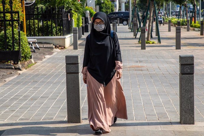 Una mujer cruza un paso de peatones en Indonesia.