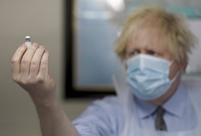 El primer ministro británico, Boris Johnson, sostiene un vial de la vacuna contra la COVID-19. 