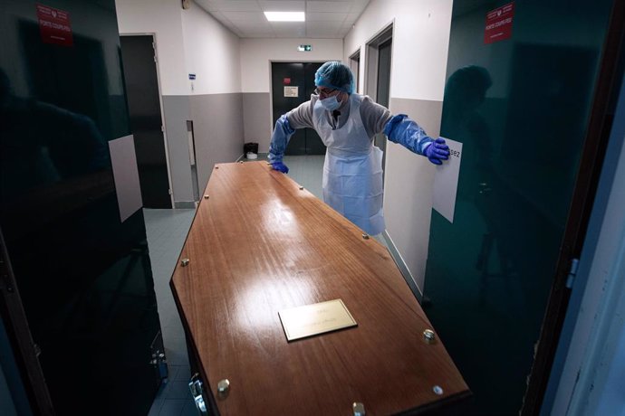 29 January 2021, France, Paris: A medical staff member at Bichat-Claude Bernard Hospital slides a casket into a mourning room in preparation for the family to say goodbye to their loved one. Photo: Joel Saget/AFP/dpa