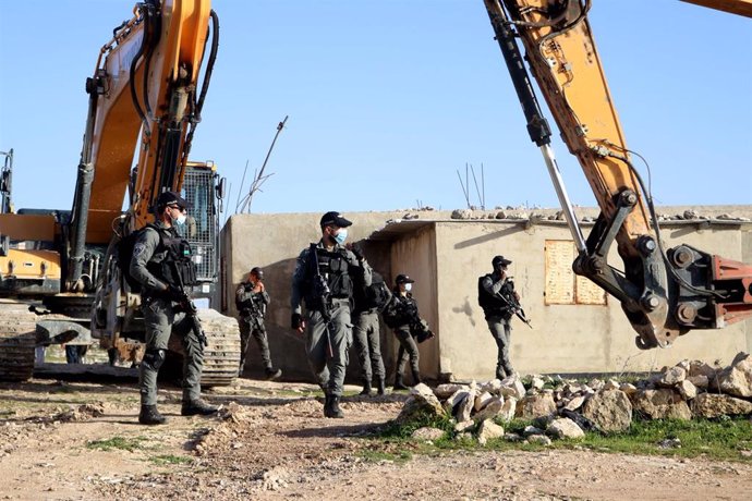 Las fuerzas de seguridad israelíes vigilan mientras las excavadoras se preparan para destruir una casa palestina en la ciudad cisjordana de Hebrón.