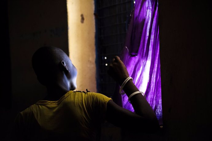Una mujer mira por la ventana durante el confinamiento en el centro de estancia temporal de Kalas, en Uganda