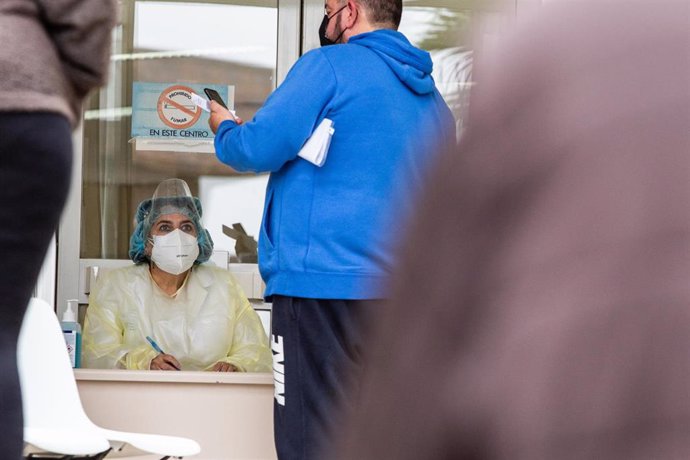 Un hombre habla con una sanitaria en la fila frente al Centro de Salud La Paz, en Badajoz, Extremadura (España).