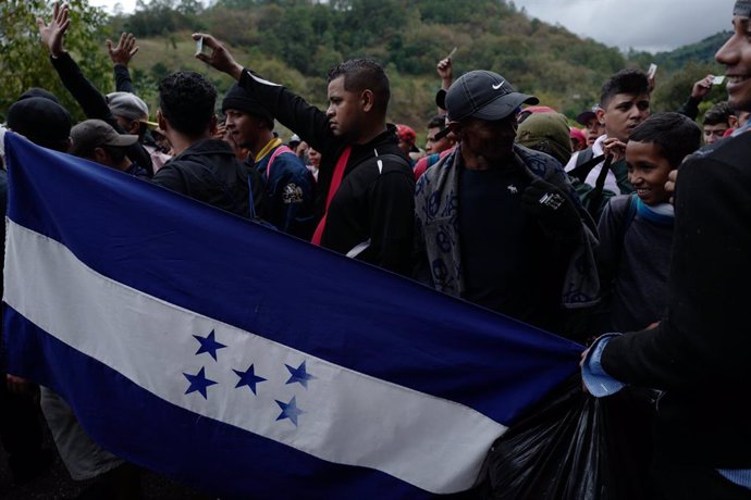 16 January 2019, Guatemala, Aguas Calientes: Migrants from Honduras hold their identity cards high as they reach the Aguas Calientes border crossing between Honduras and Guatemala, as they take their way to the north, plans to immigrate to the USA durin