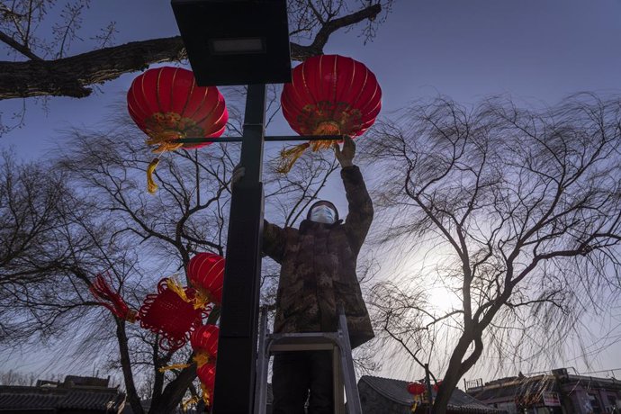 Un trabajador cuelga un farolillo en Pekín como parte de la decoración del festival de primavera.