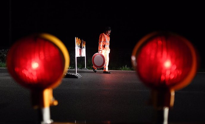 15 May 2020, Bavaria, Griesen: An employee of the road maintenance department removes a "no entry" traffic sign at the Griesen border crossing and carries it to the car. At midnight, many borders with neighbouring Austria were reopened  after a two-mont