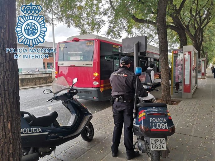 Un agente junto a un bus de Tussam junto al centro comercial Plaza de Armas