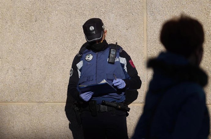 Un agente de la Policía Municipal de Madrid controla la fila de personas que esperan en las inmediaciones del Centro Municipal de Mayores Príncipe de Asturias, en la zona de salud básica de Doctor Cirajas, en Ciudad Lineal, a realizarse un test de antíg