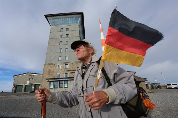 03 October 2020, Saxony-Anhalt, Schierke: Record hiker Benno Schmidt holds a national flag as he hikes to the Brocken during the German Unity Day. Photo: Matthias Bein/dpa-Zentralbild/dpa